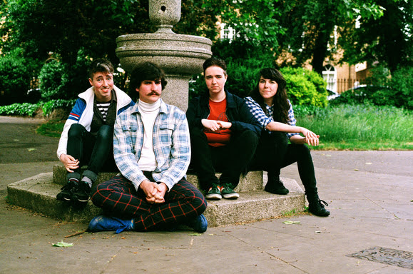 Promo image of The Spook School band sitting in front of a fountain