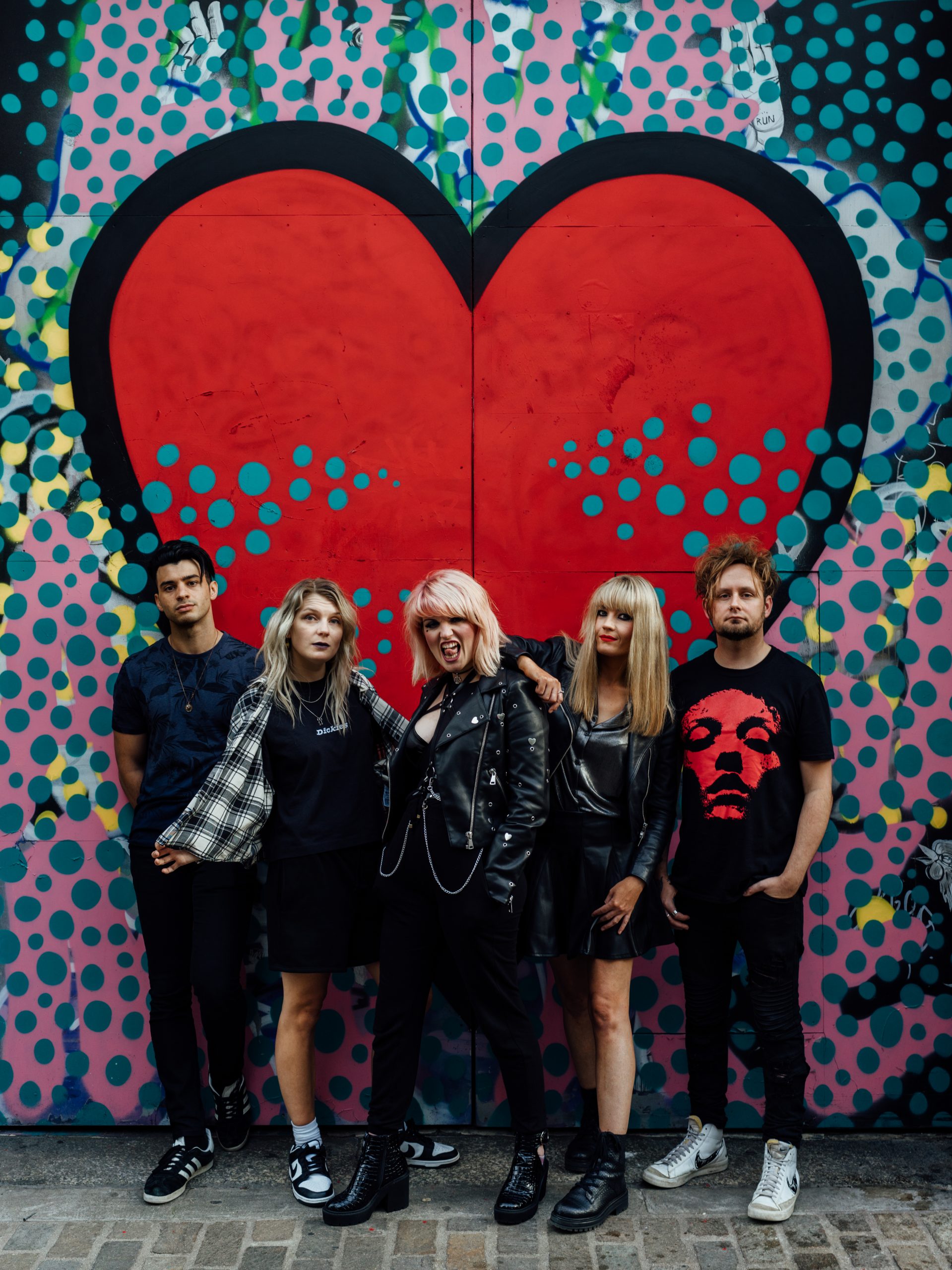 The five members of band Salvation Jayne in front of a red heart on the wall