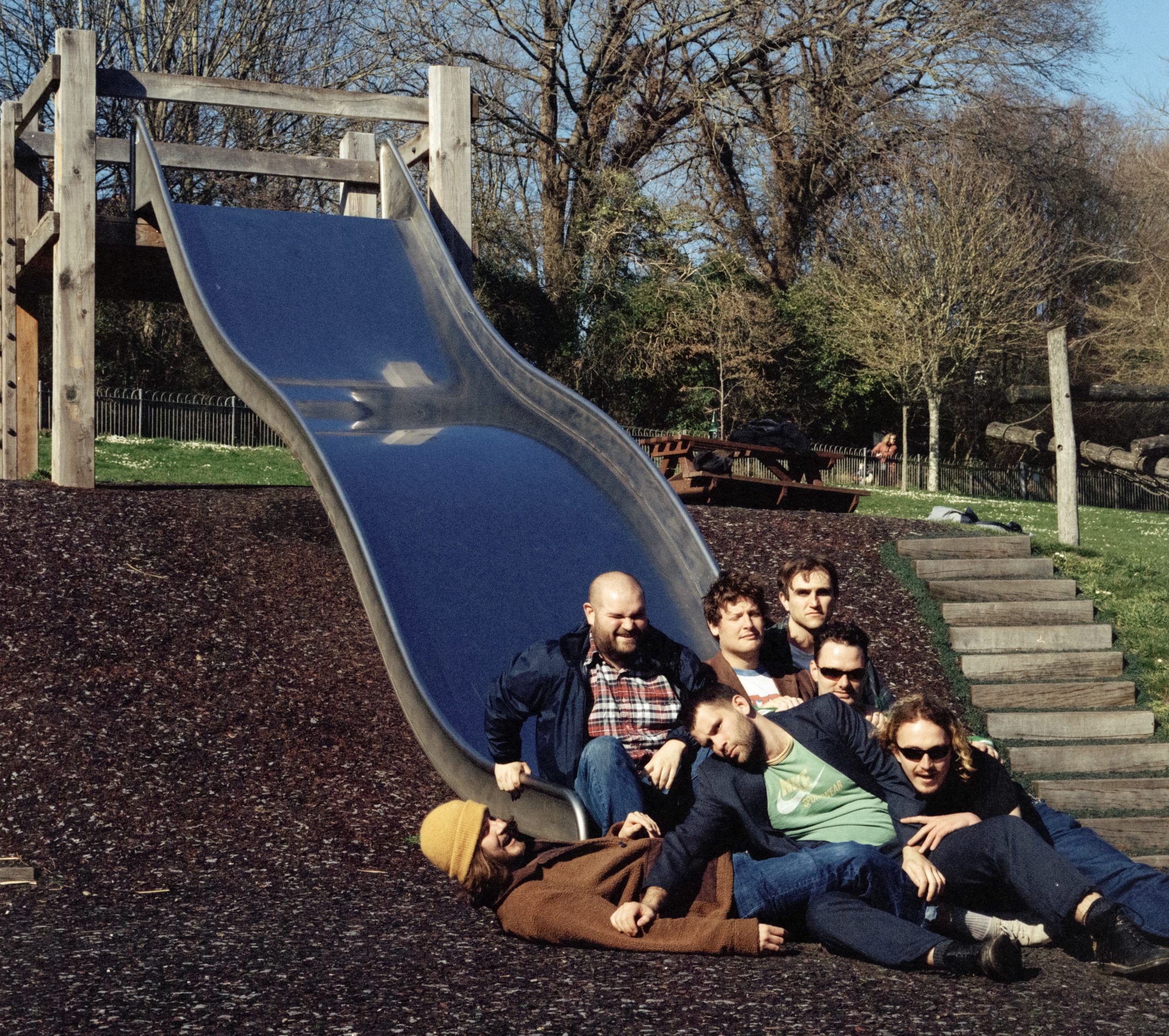 The seven piece band KEG in a playground at the bottom of a slide