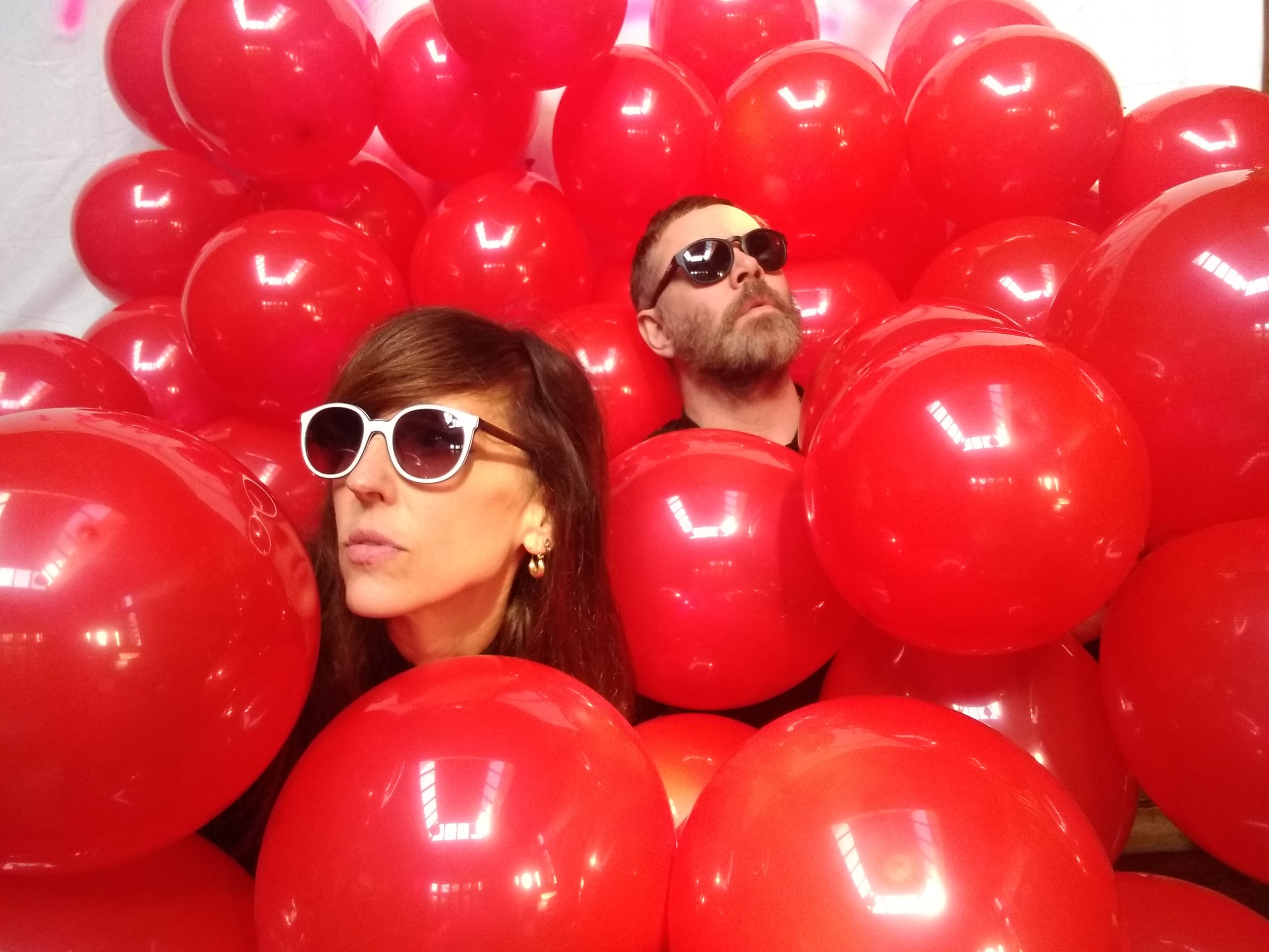 The two members of the band Lunge in amongst loads of reds balloons
