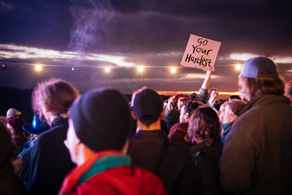 A person holds up a sign in the crowd that reads "Go your hardest".